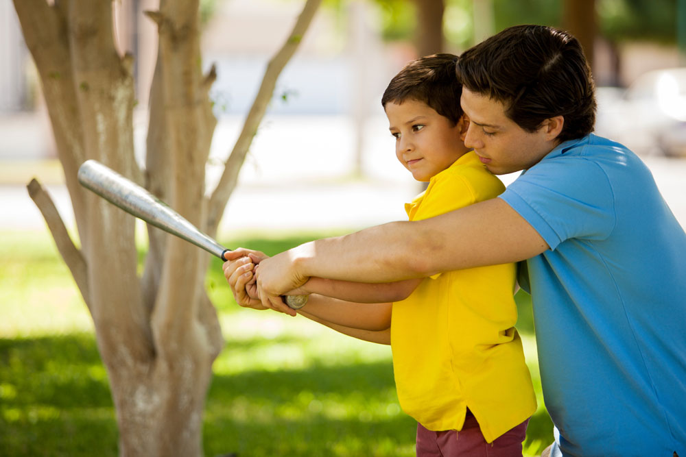 man teaching child to hit a ball