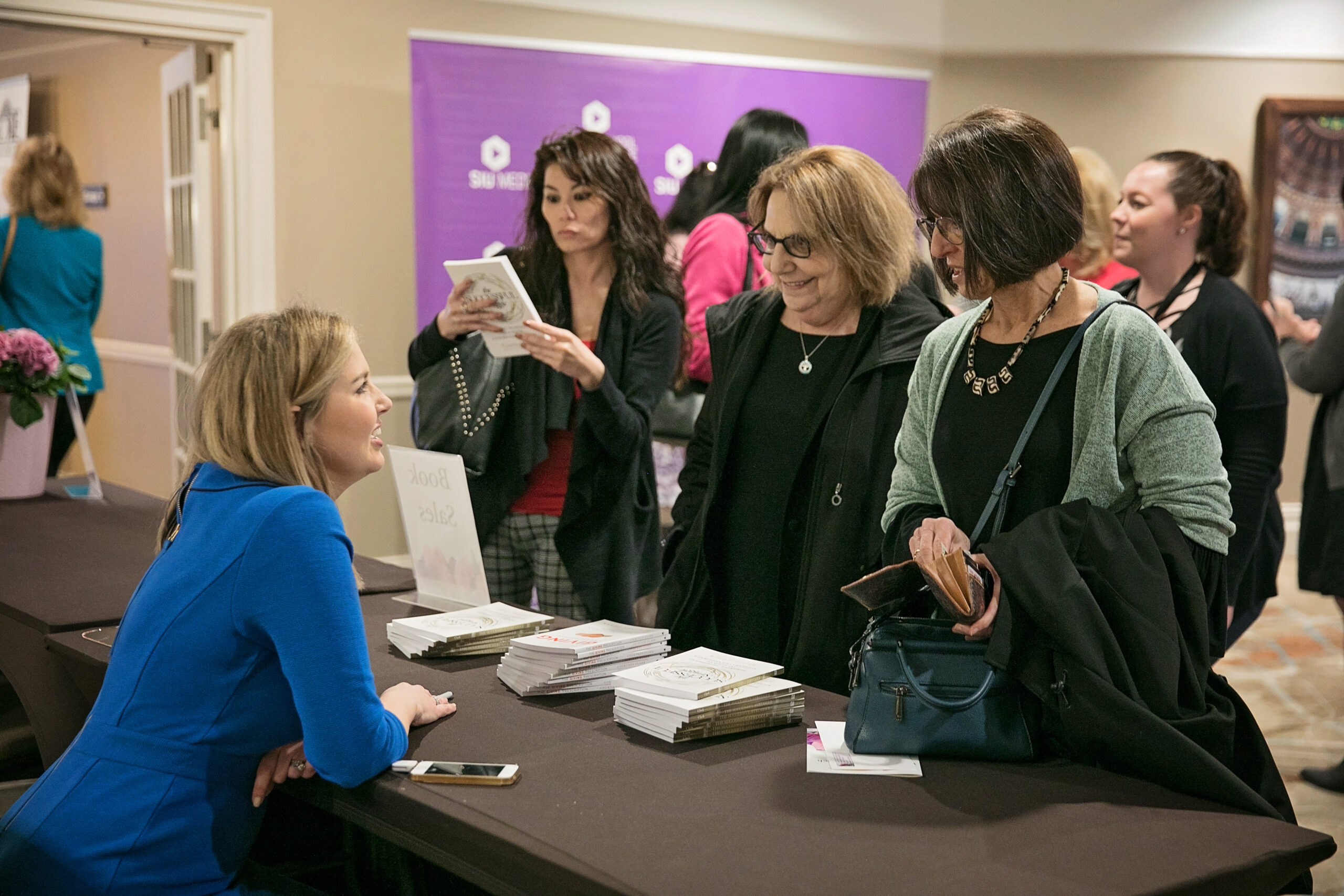 Resilience and change keynote speaker Courtney Clark signing books and talking with audience members after a keynote speech.
